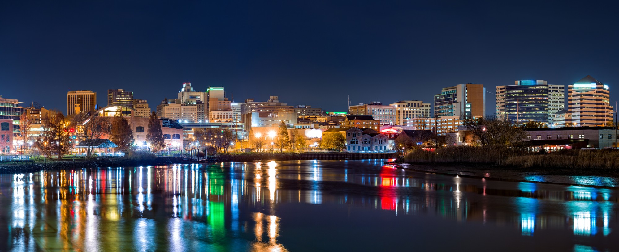 The Wilmington, Delaware riverfront skyline at night, reflected on the Christina River